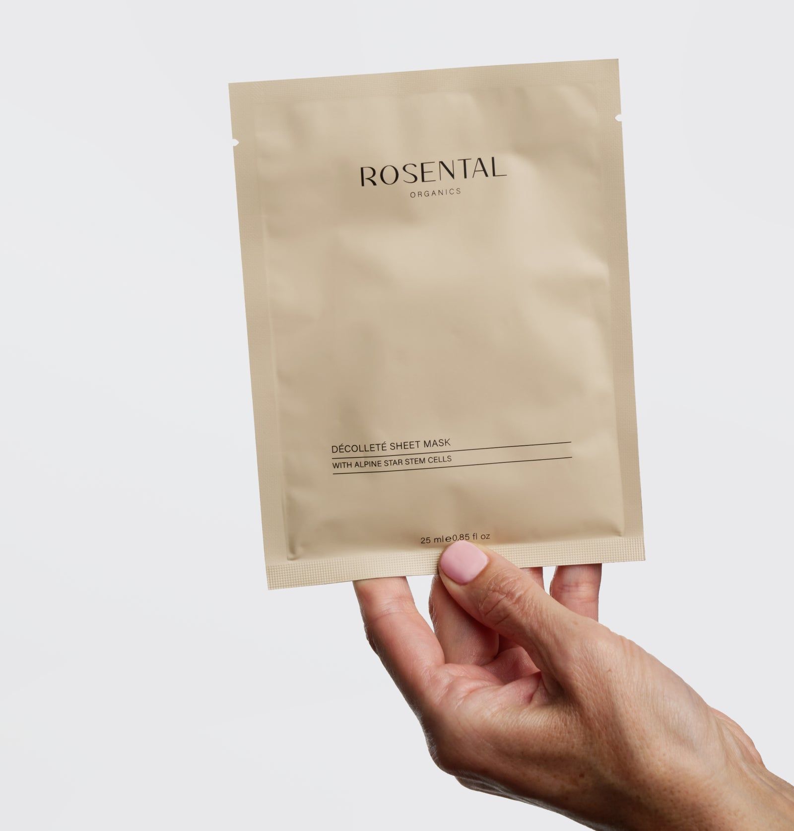 Hand hält eine beige Verpackung. Produktname und Schriftzug sichtbar. Text: Décolleté Sheet Mask, mit Alpine Star Stem Cells.