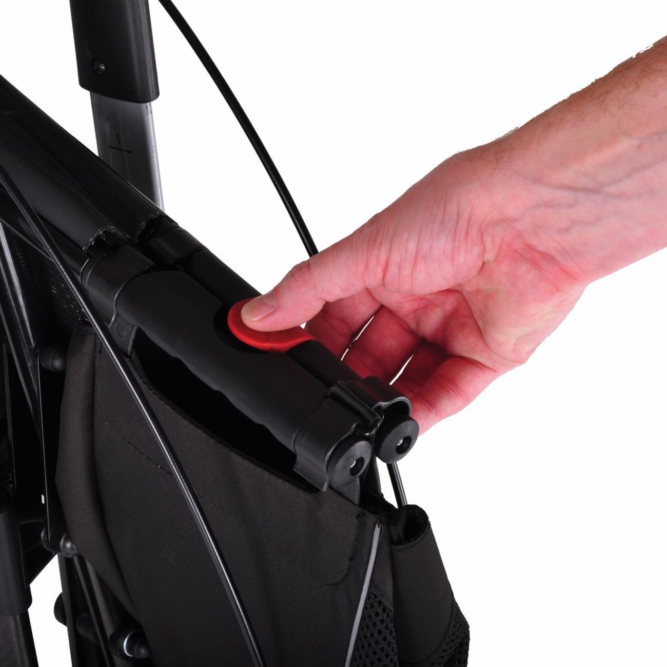 Nahaufnahme eines Rollators mit rotem Knopf. Eine Hand drückt den Knopf.