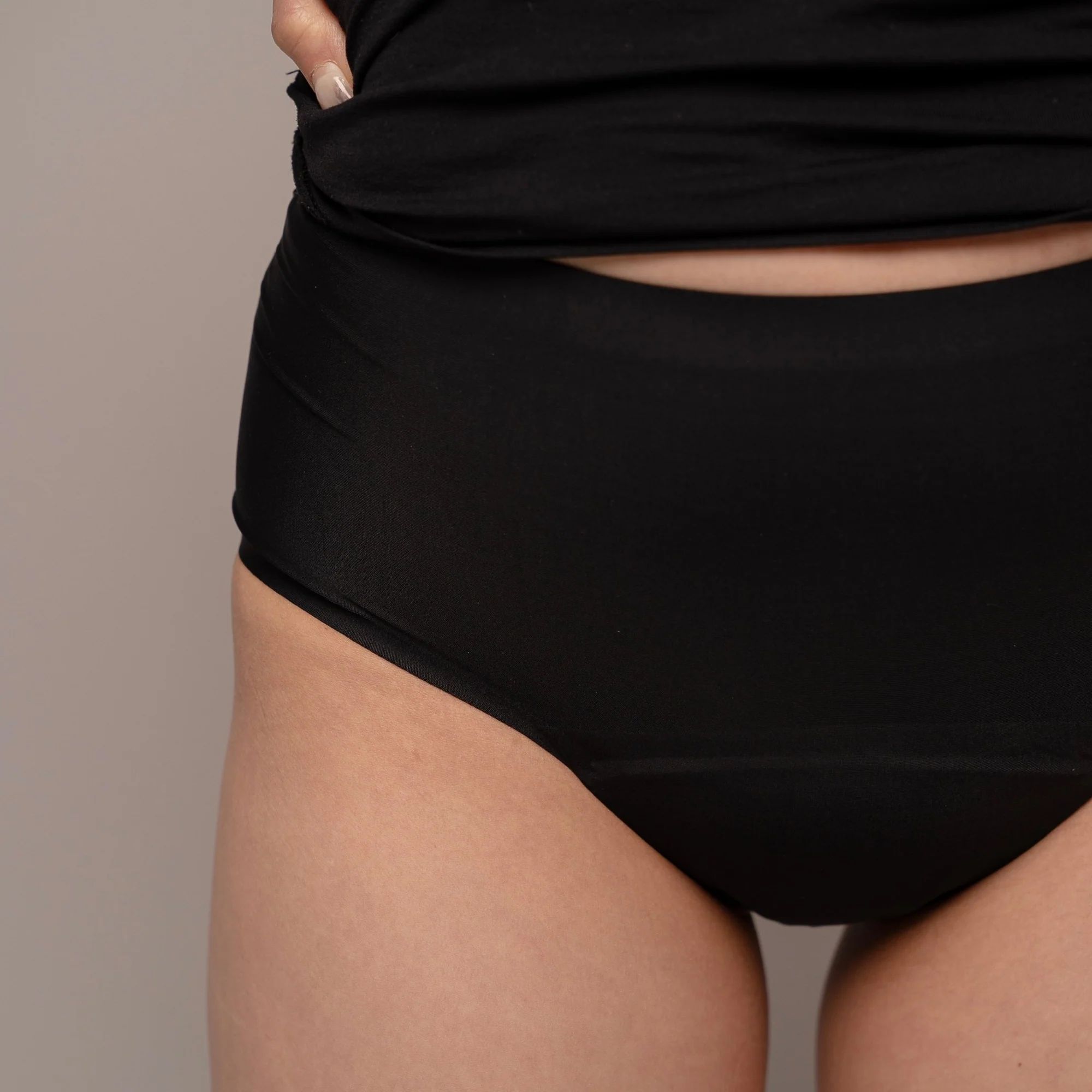 Schwarzer Slip. Person trägt schwarzes Tanktop. Nahaufnahme. Hautfarbene Hände.