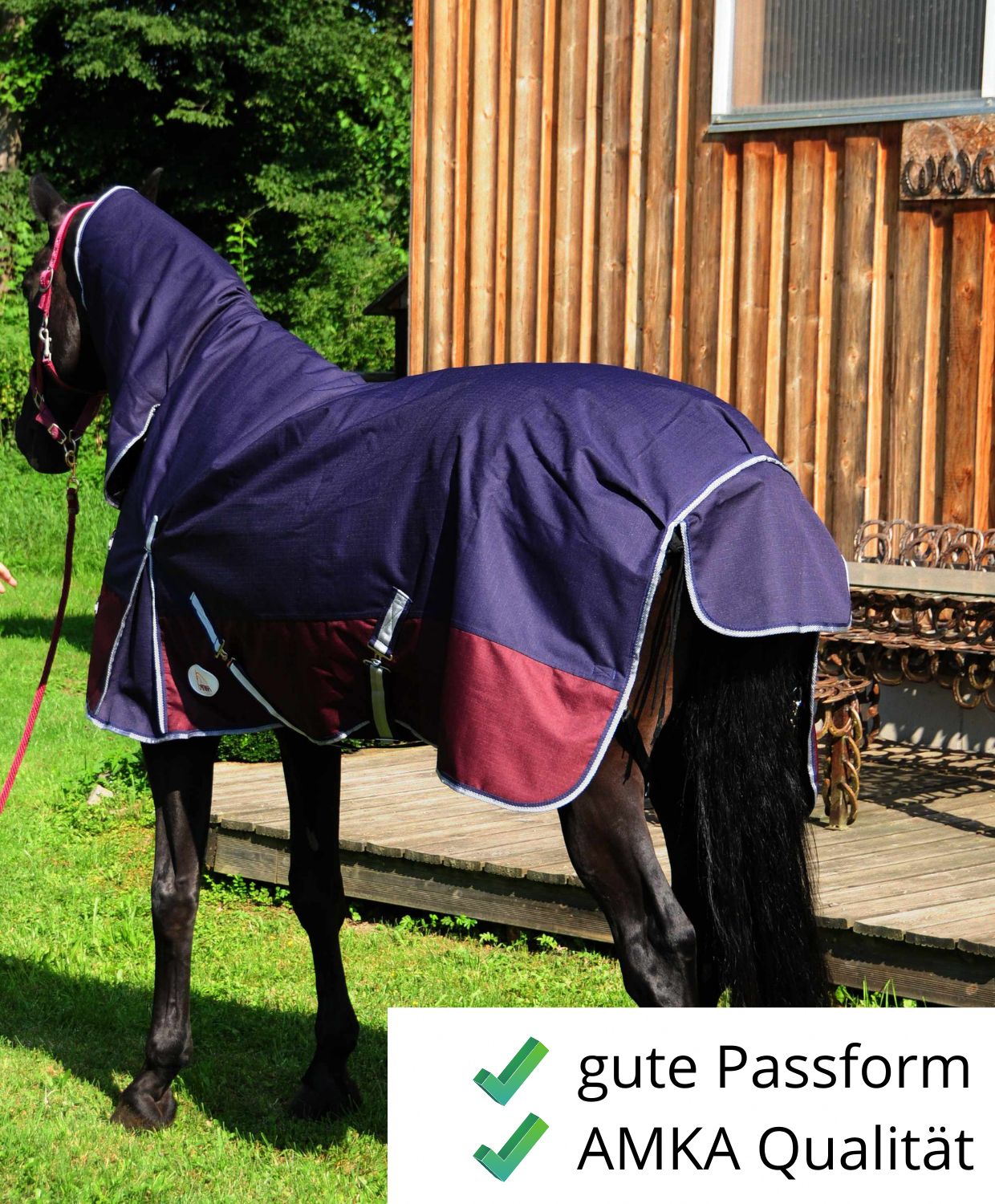 Pferdedecke, dunkelblau mit bordeauxfarbenem Saum. Auf einem Pferd. Text: gute Passform, AMKA Qualität.