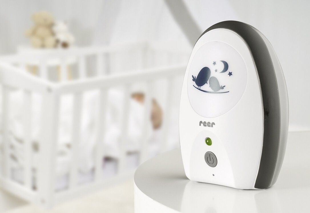 Babyphone mit Nachtlichtfunktion neben einem Kinderbett.