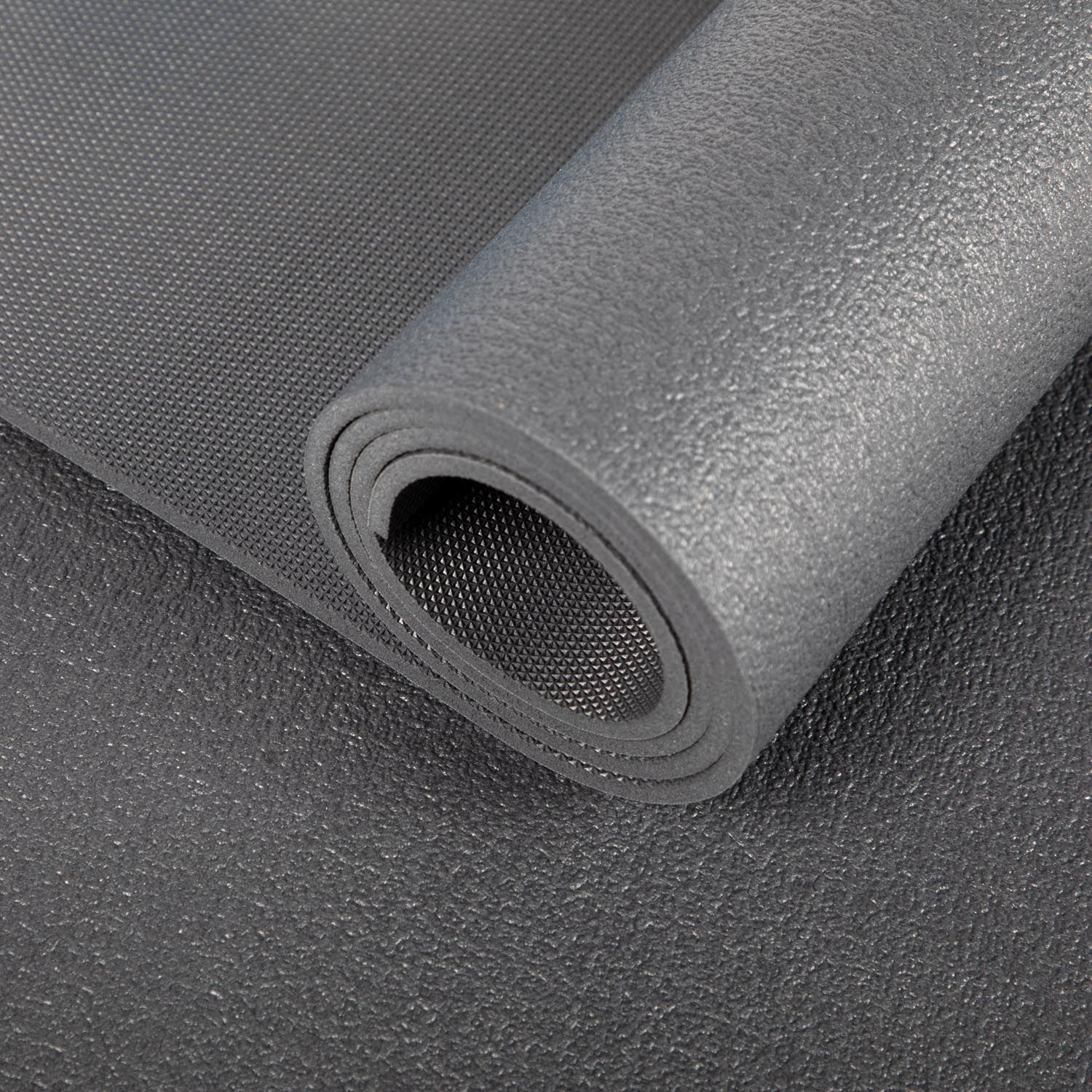 Dunkelgraue Yogamatte, gerollt. Strukturierte Oberfläche, Nahaufnahme.
