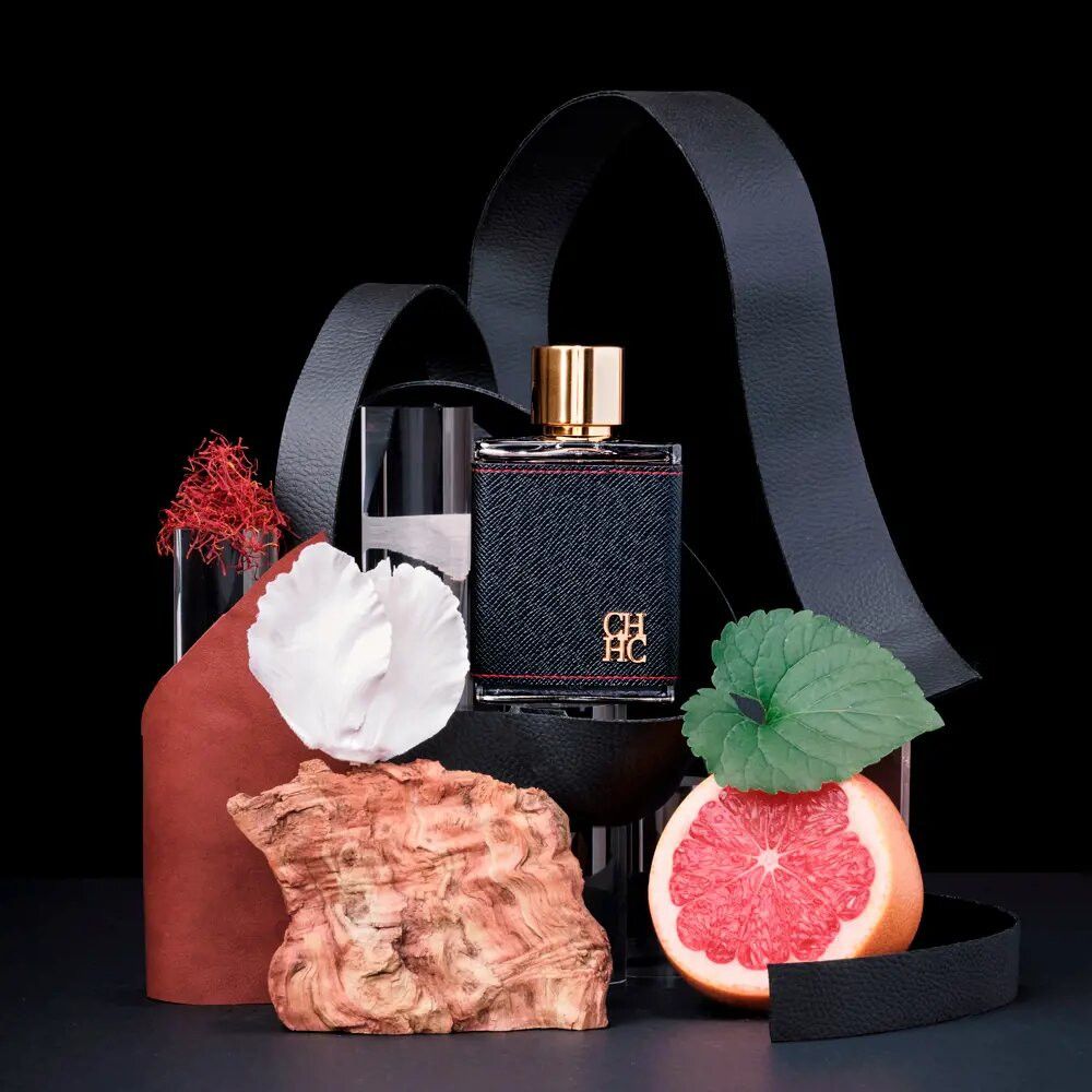 Eau de Toilette-Flakon mit schwarzem Lederimitat, roter Naht und goldenem Verschluss. Auf schwarzem Hintergrund mit Dekoration.
