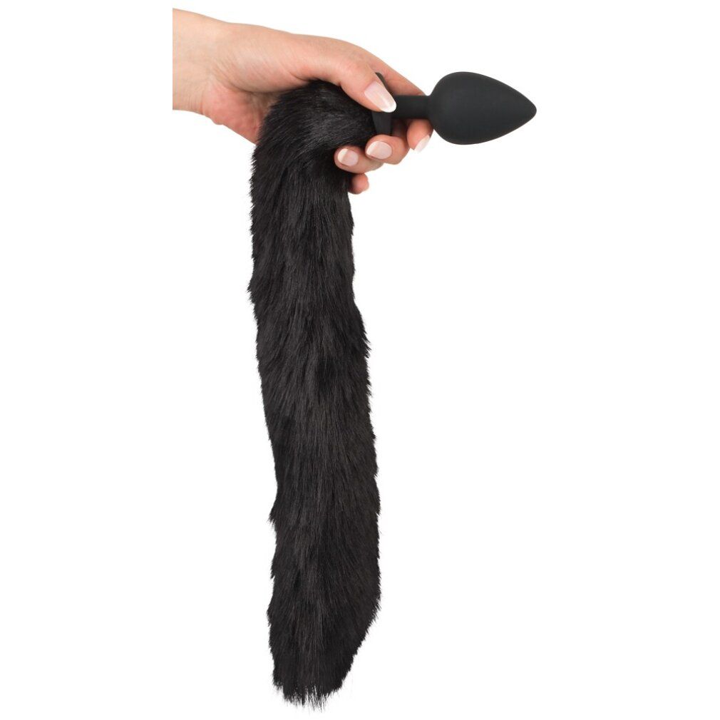 Hand hält schwarzen, pelzigen Schwanz mit schwarzem Plug. Auf weißem Hintergrund.