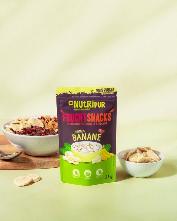 Produktpräsentation mit gefriergetrockneten Bananensnacks, einer Schüssel Müsli und einer Packung NutriPur Frucht Snacks.