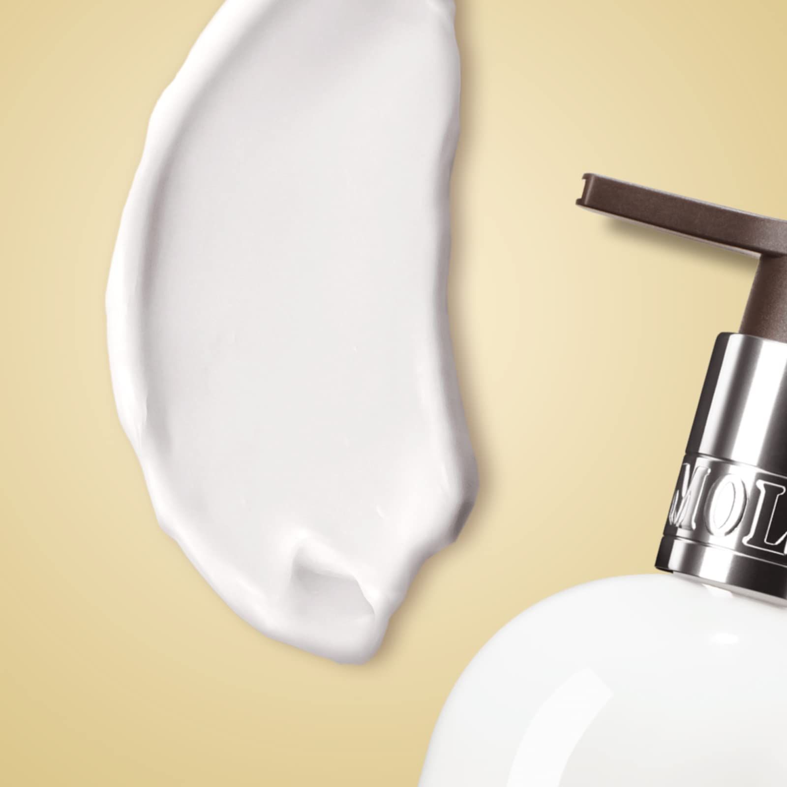 Weiße Bodylotion-Flasche mit Pumpspender, silbernem Halsband und Etikett.