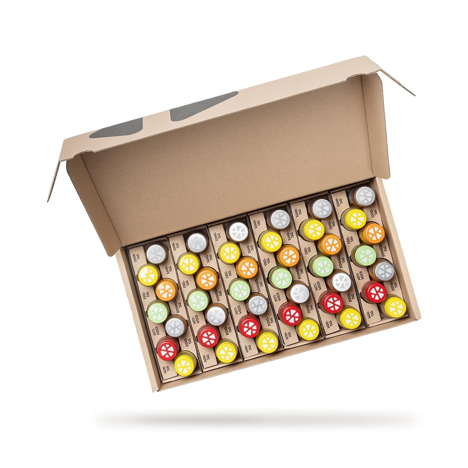 Geöffnete Pappschachtel mit mehreren kleinen Flaschen. Deckel in verschiedenen Farben: gelb, orange, rot. Produktname nicht sichtbar.