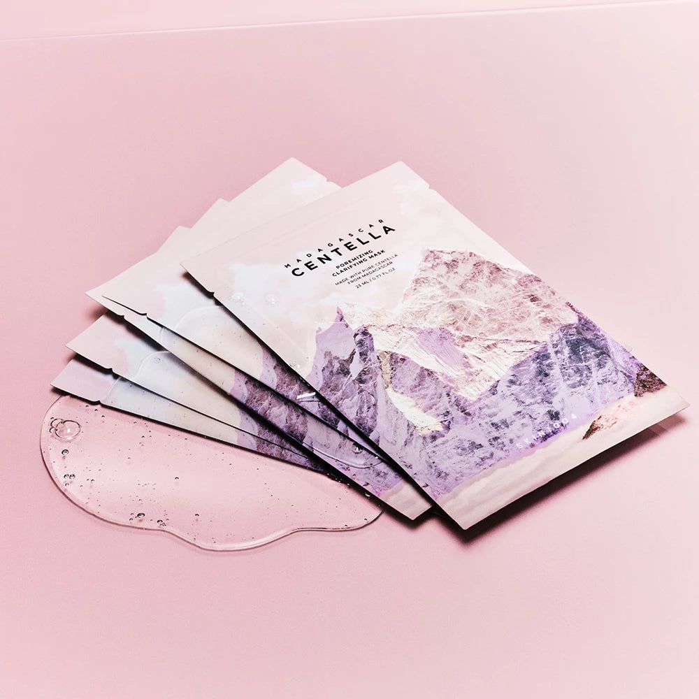 Mehrere Gesichtsmasken auf rosa Hintergrund. Daneben eine transparente Flüssigkeit.