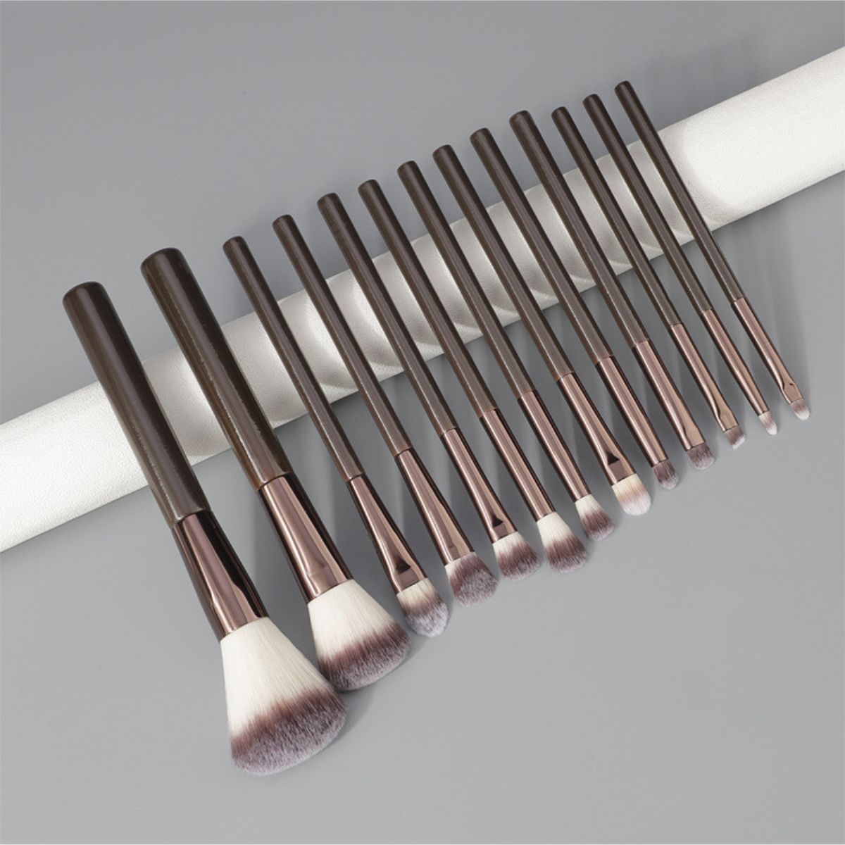 Ein Set aus 12 dunklen Make-up-Pinsel mit silbernen Zwingen und flauschigen Borsten.
