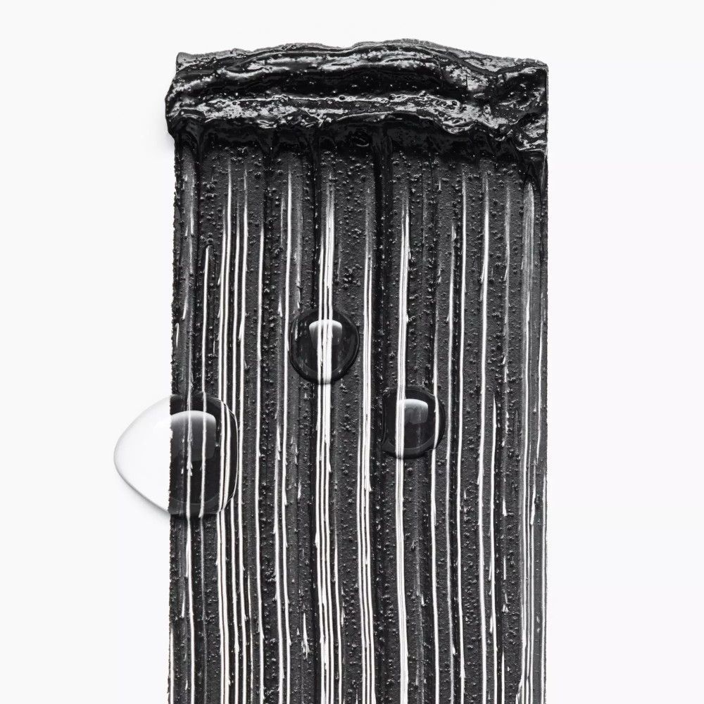 Schwarze Mascara-Textur mit Wassertropfen. Vertikale Linien. Weiße Hintergrund.
