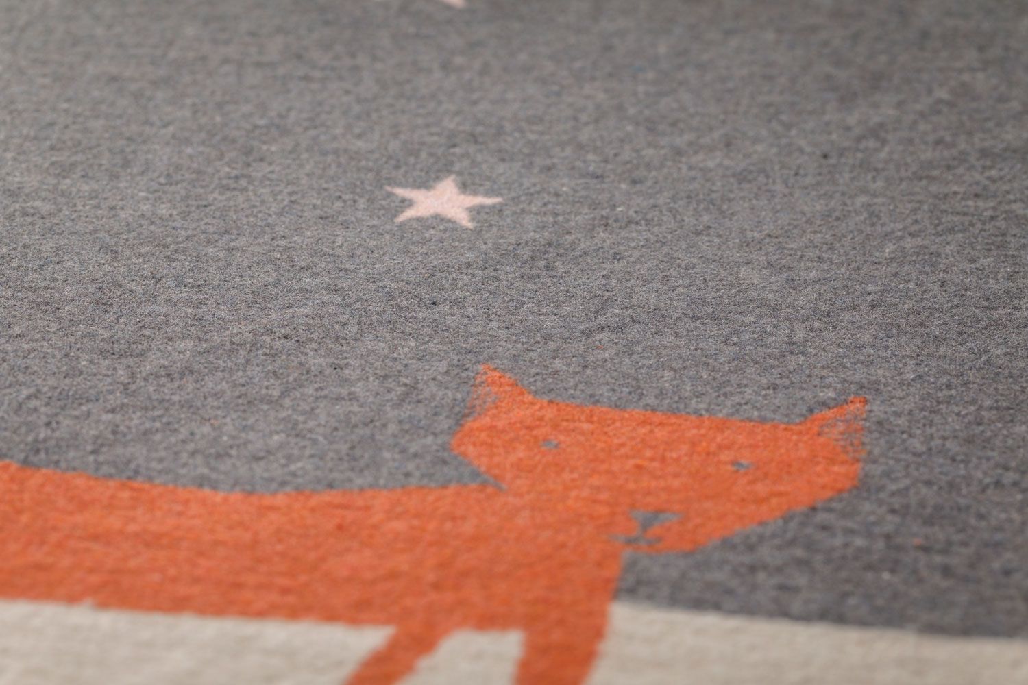 Graue Decke mit orangefarbenem Fuchs und rosa Sternen.