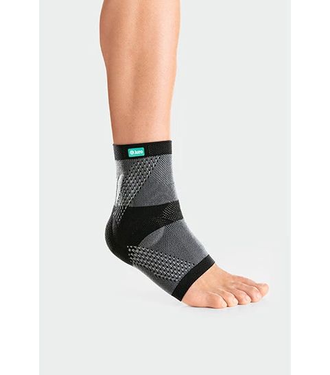 Knöchelbandage JuzoFlex Malleo Xtra am Fuß. Grau-schwarzes Material mit Logo. Zeigt das Produkt am Knöchel.