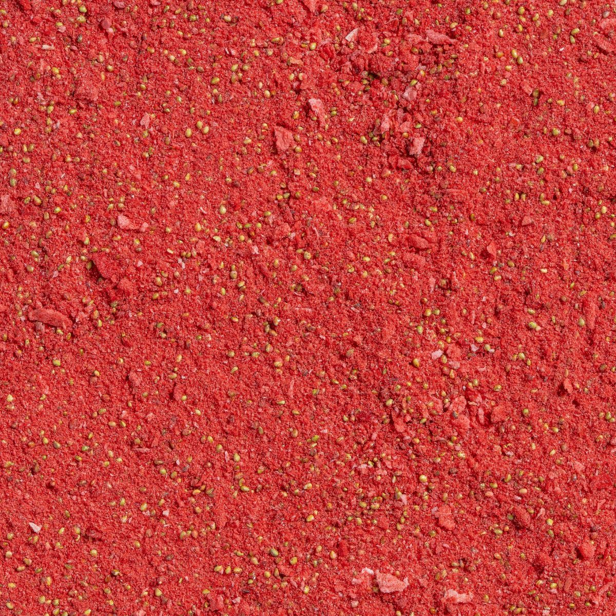 Nahaufnahme von rotem Erdbeerpulver mit kleinen gelben Partikeln.
