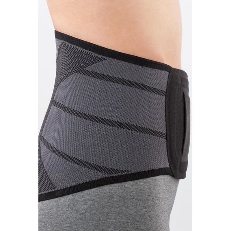 Graue Rückenorthese. Schwarze Akzente. Mesh-Einsätze. Auf der Seite einer Person getragen. Schwarzer Saum.