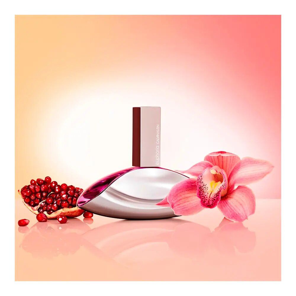 Parfümflasche mit Granatapfel und Orchidee. Flasche: oval, silberfarben mit pinkfarbenem Inhalt. Orchidee: pink. Hintergrund: orange.