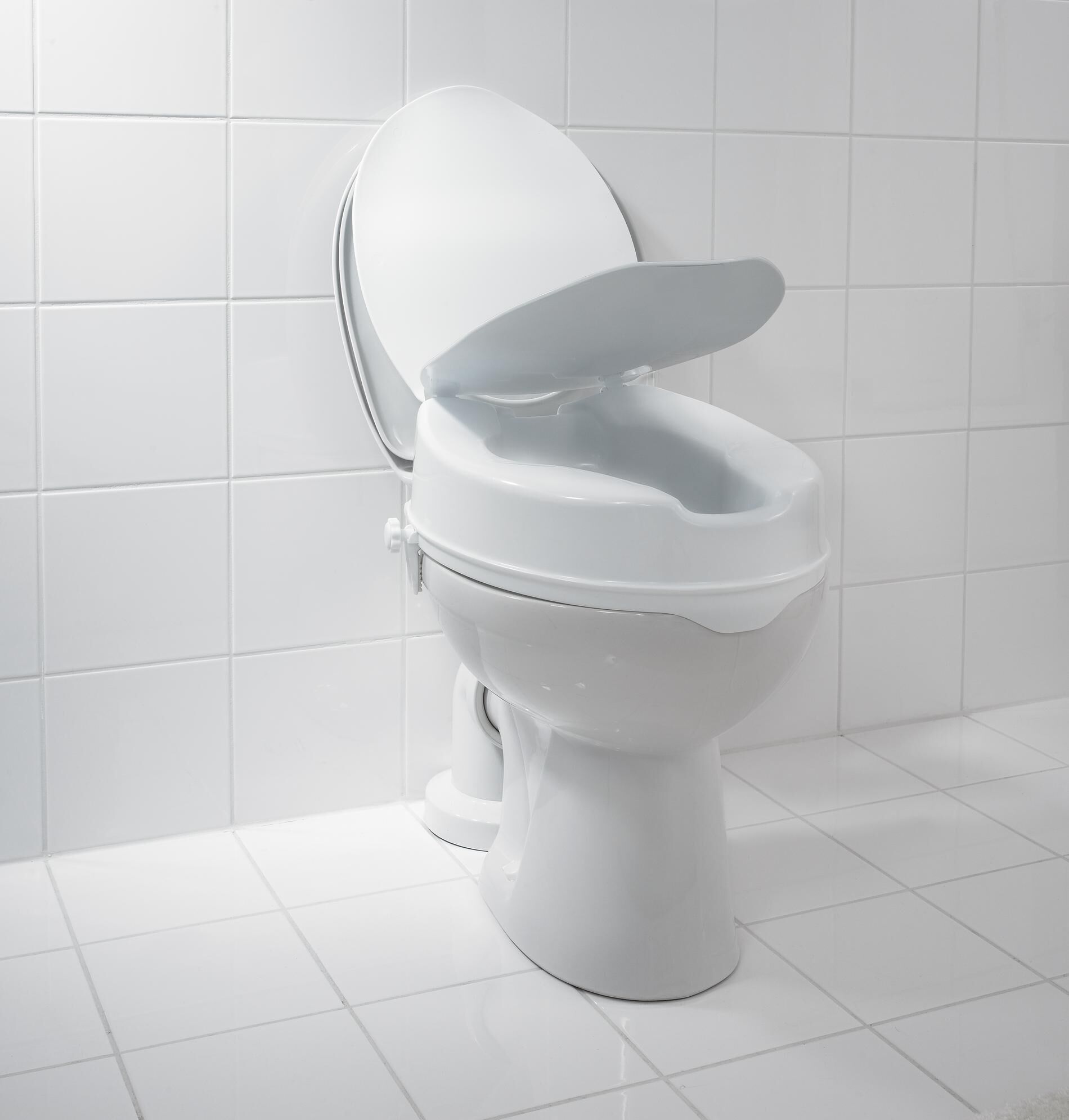 WC-Sitzerhöhung, weiß, auf einem WC montiert. Deckel geöffnet. Fliesen im Hintergrund.