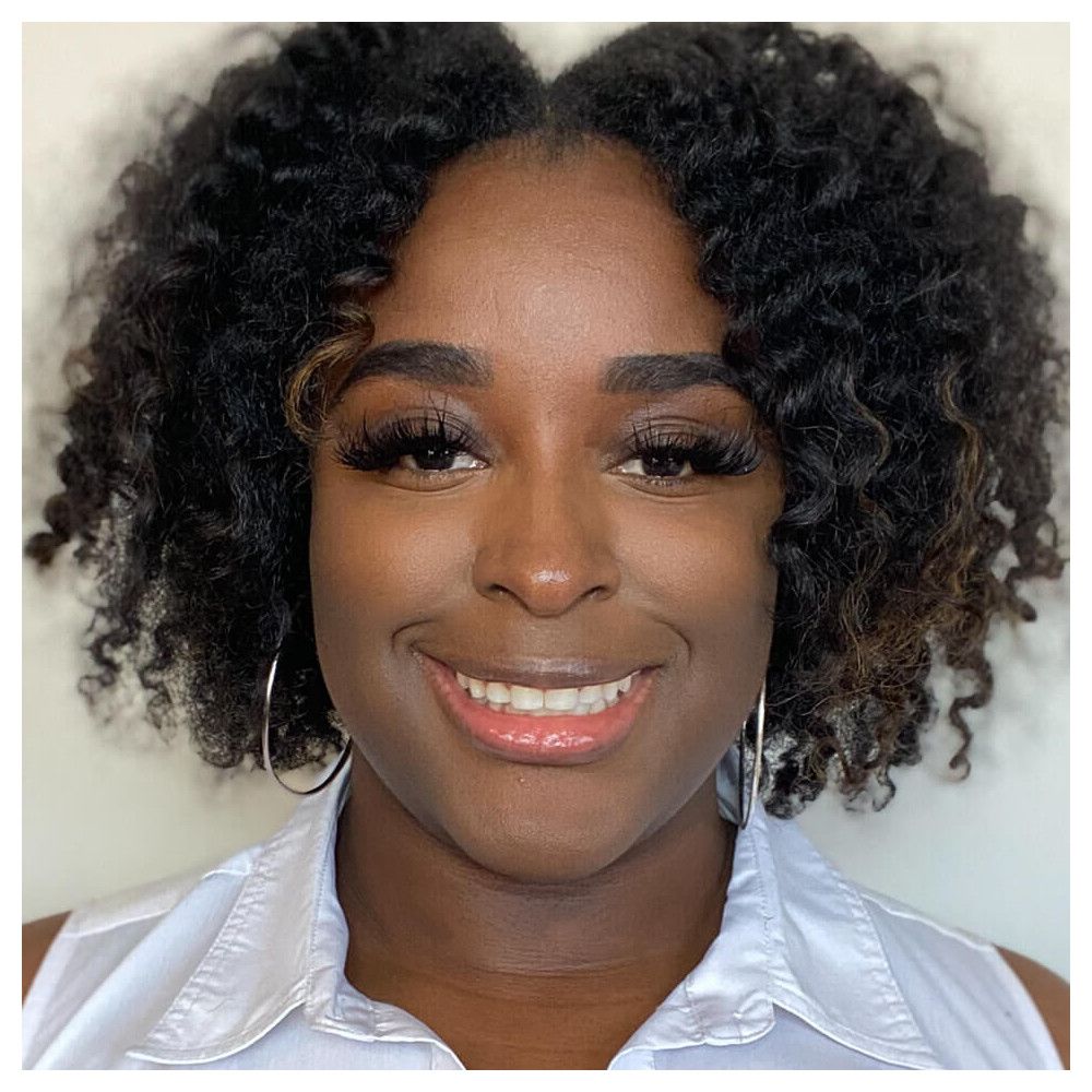 Porträt einer lächelnden Frau mit Locken und Ohrringen. Hautton, Make-up.