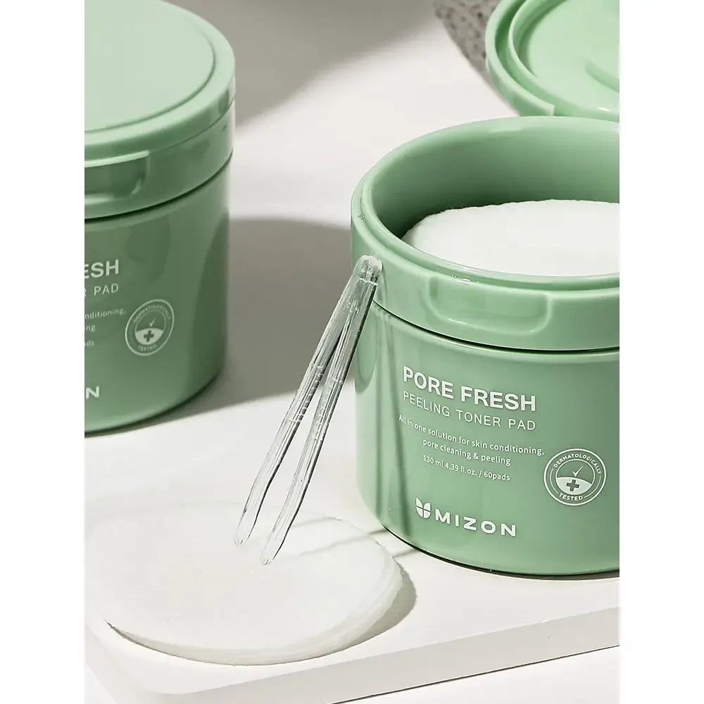 Grüne Dose mit Toner-Pads, transparente Pinzette, Pad daneben. Aufschrift: Pore Fresh Peeling Toner Pad. Marke: MIZON.