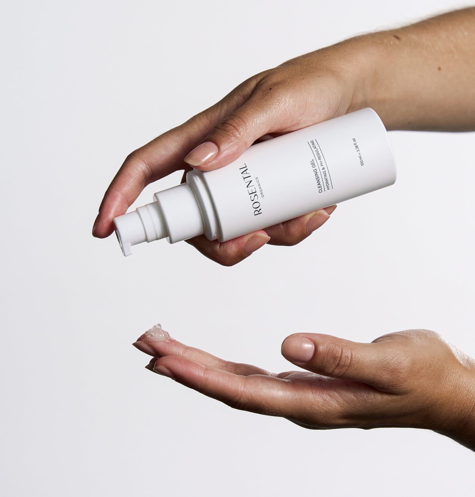 Hände halten eine weiße Flasche Cleansing Gel. Gel wird in die andere Hand gedrückt.