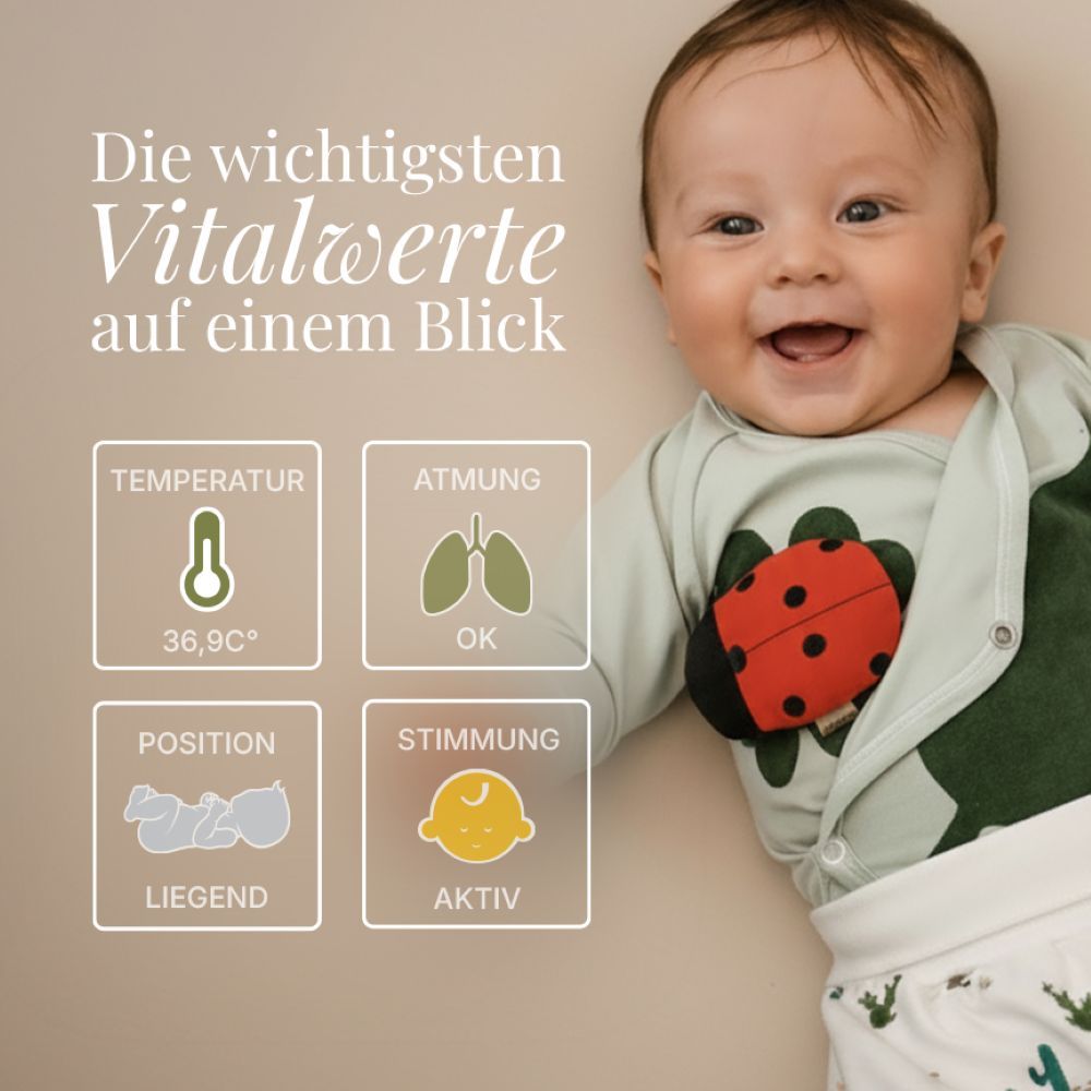 Baby mit grünem Body und Marienkäfer-Applikation. Vitalwerte-Anzeige: Temperatur, Atmung, Position, Stimmung.