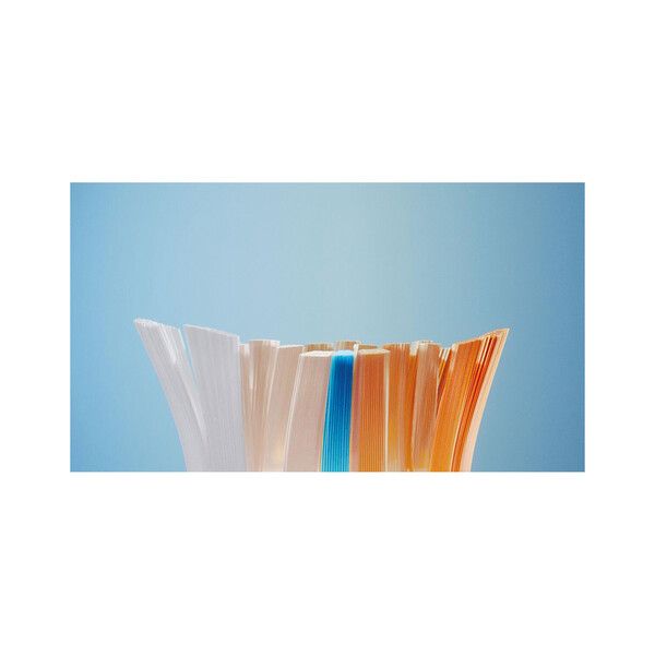 Nahaufnahme der Borsten einer Philips Ersatz-Zahnbürste. Borsten in Weiß, Orange und Blau, vor blauem Hintergrund.