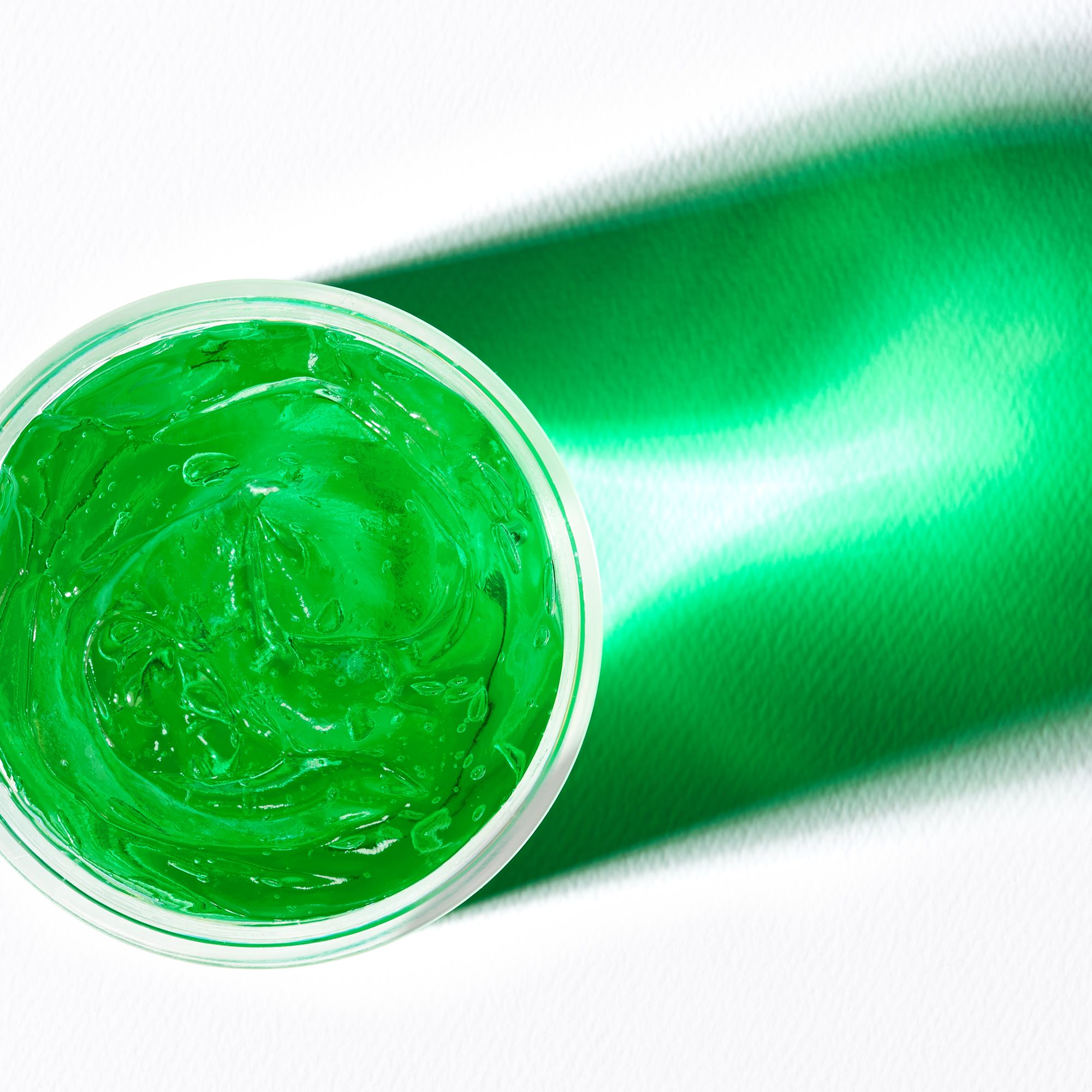 Draufsicht auf grünes Gel in einem durchsichtigen Behälter. Ein Schatten wirft sich auf die Oberfläche.