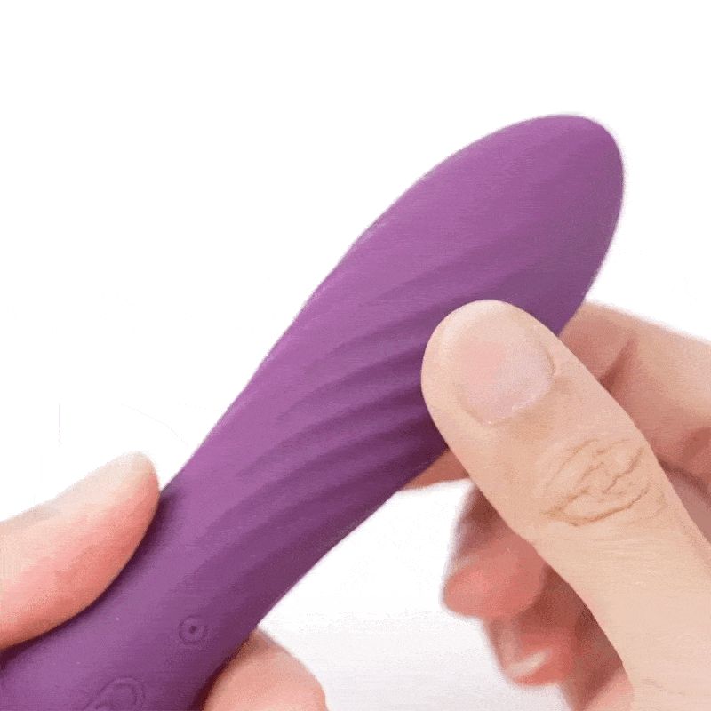Lila Vibrator, wellenförmige Oberfläche, wird von einer Hand gehalten.