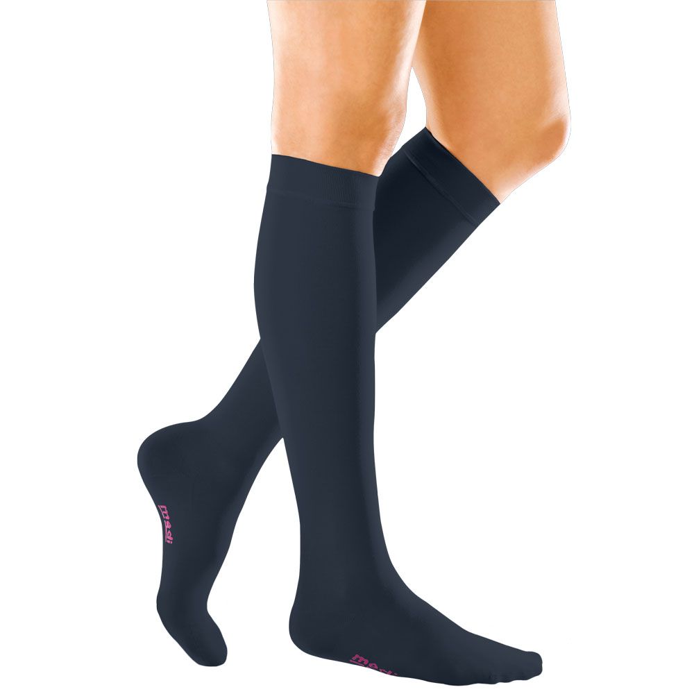 Dunkelblaue Kompressionsstrümpfe am Bein. Rosa Logo am Fuß. Strümpfe reichen bis zum Knie.