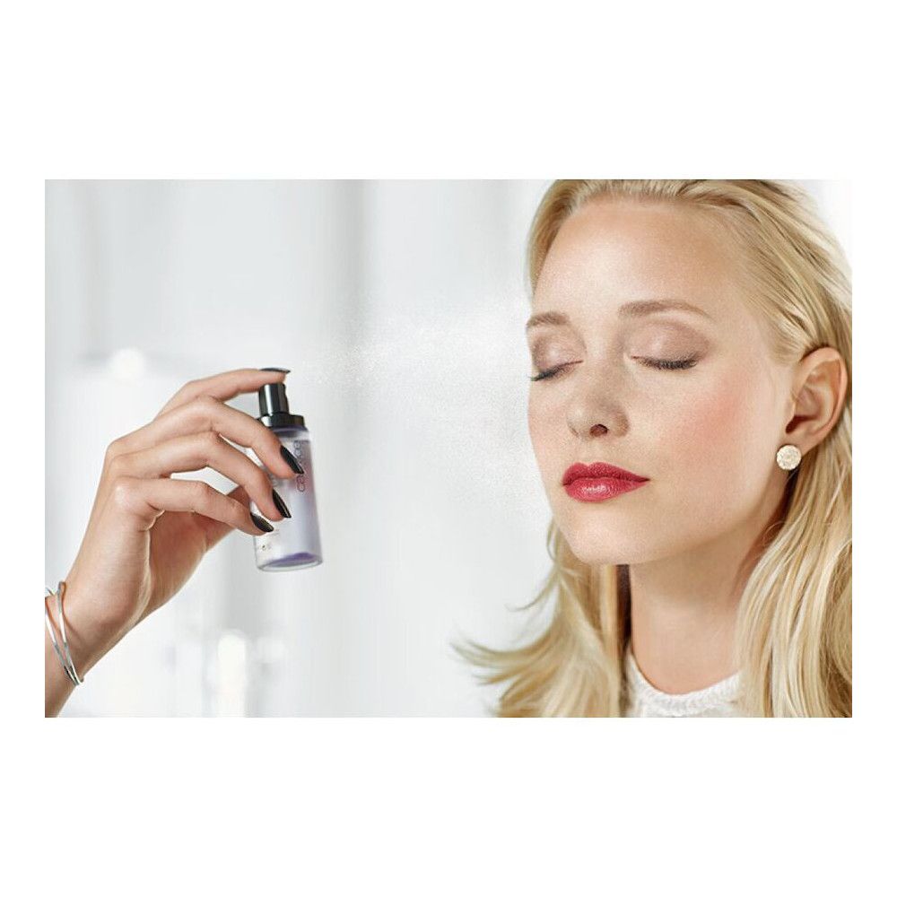 Eine Hand sprüht ein Spray auf das Gesicht einer Frau. Das Spray ist Catrice Prime and Fine.