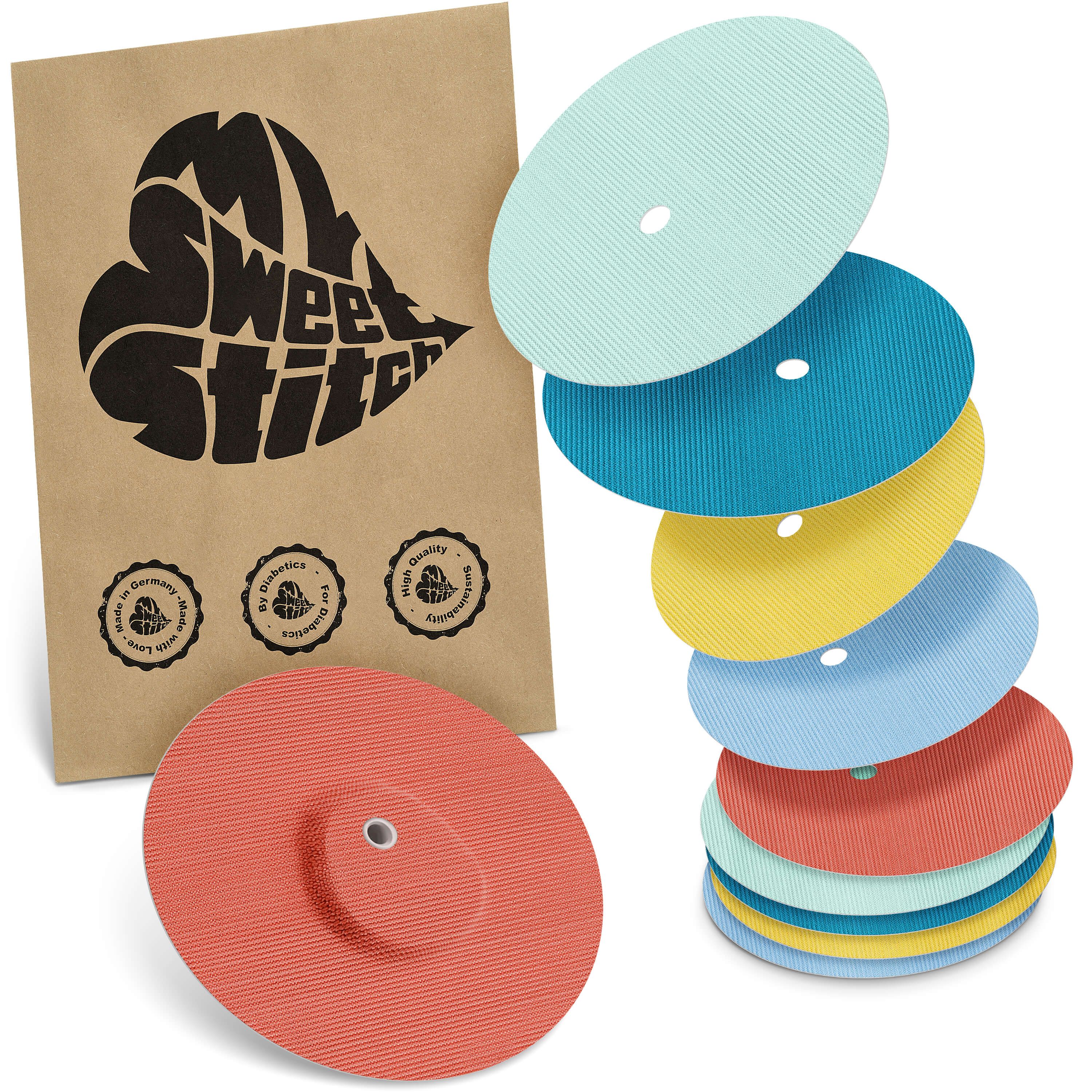Mehrfarbige Fixierpflaster, teilweise gestapelt, mit Loch. Braune Verpackung mit Logo und Qualitätssiegeln.