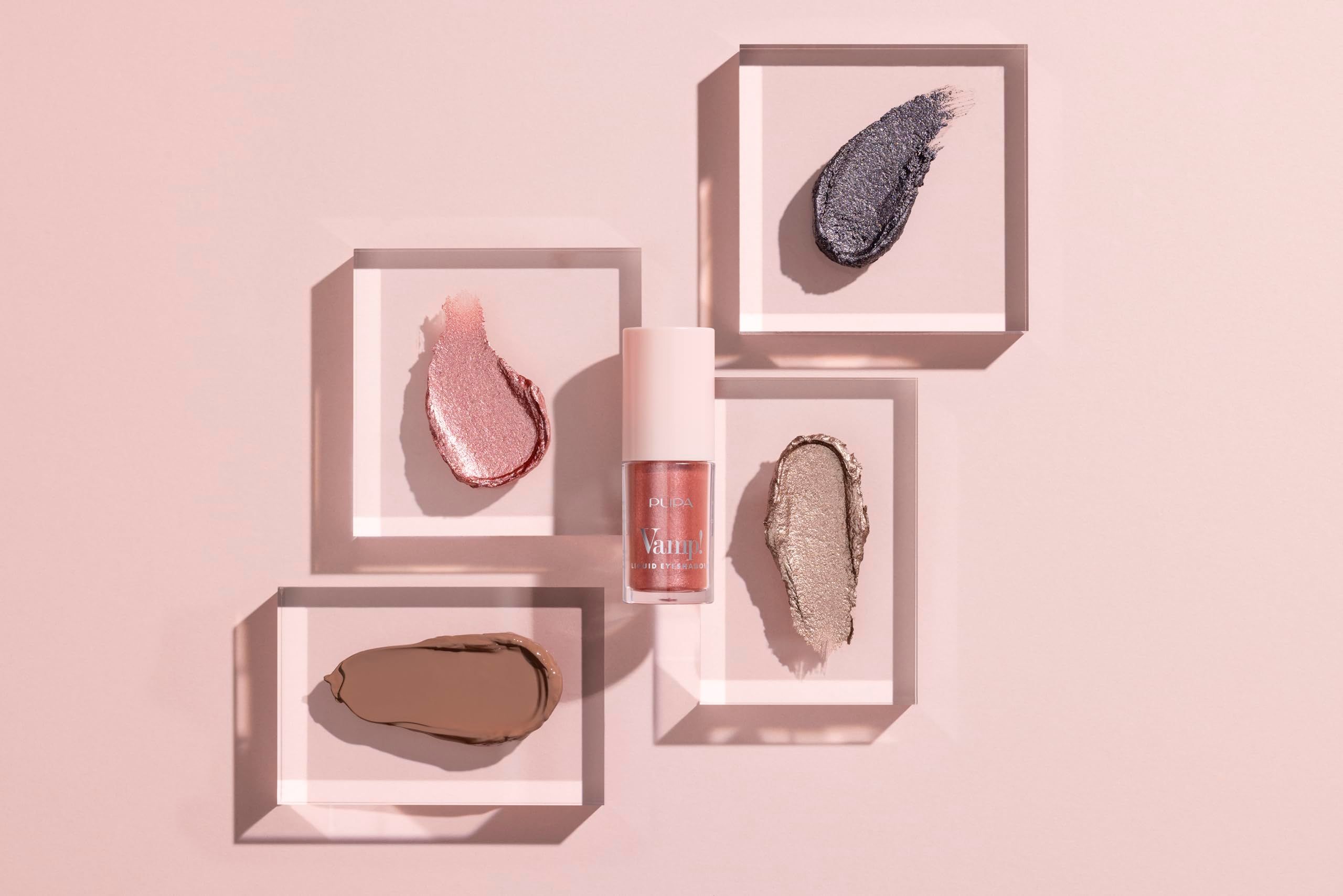 Pupa Milano Vamp! Liquid Eyeshadow Flasche und vier Lidschatten-Swatches. Verschiedene Farben auf transparenten Blöcken.