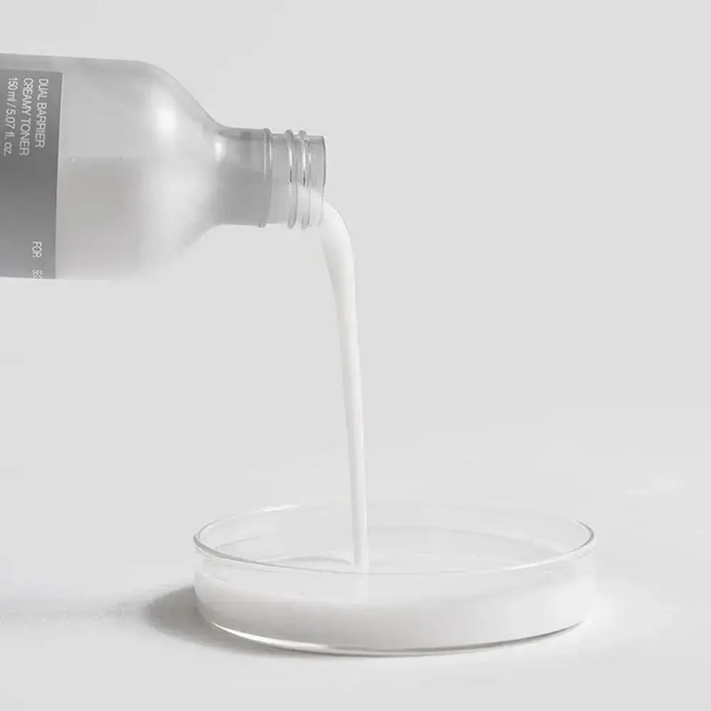 Weiße Flüssigkeit wird aus einer Flasche in eine Glas-Petrischale gegossen.