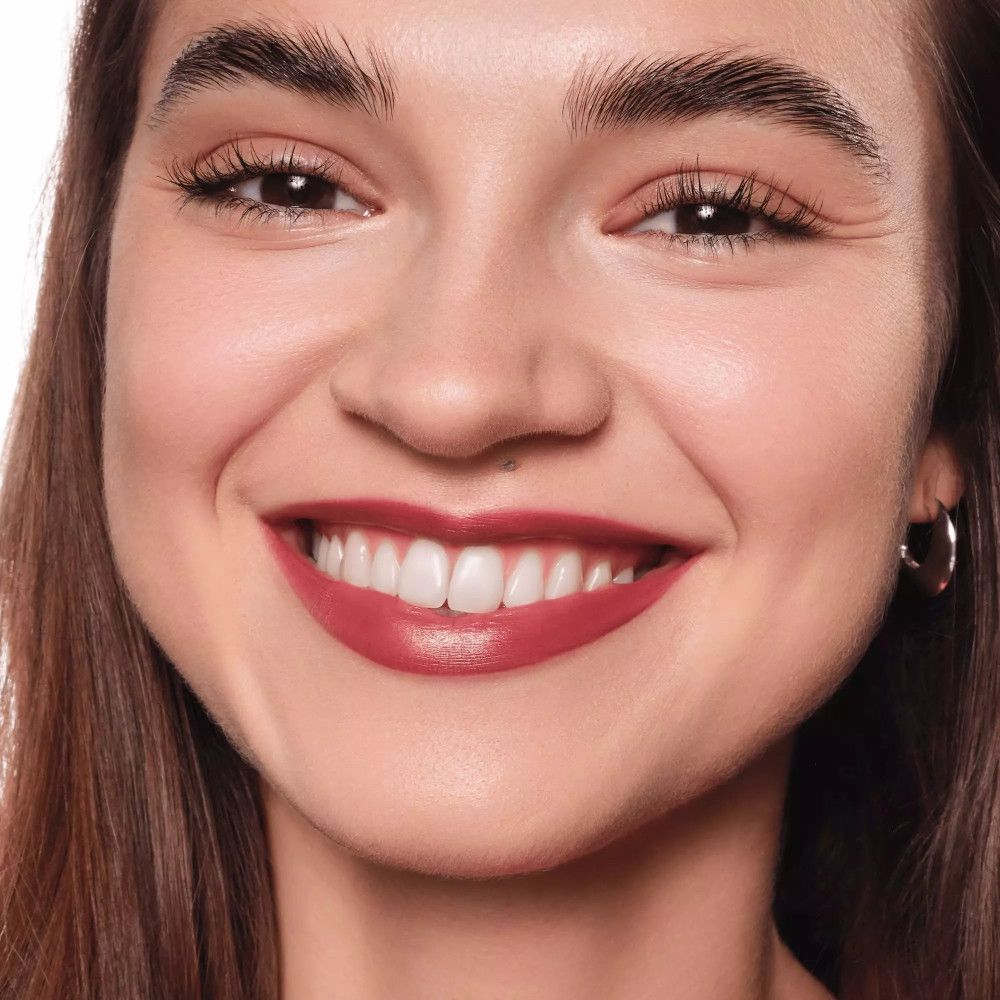 Nahaufnahme eines lächelnden Gesichts mit Lippenstift. Die Lippen sind mit einem roten Lippenstift geschminkt.