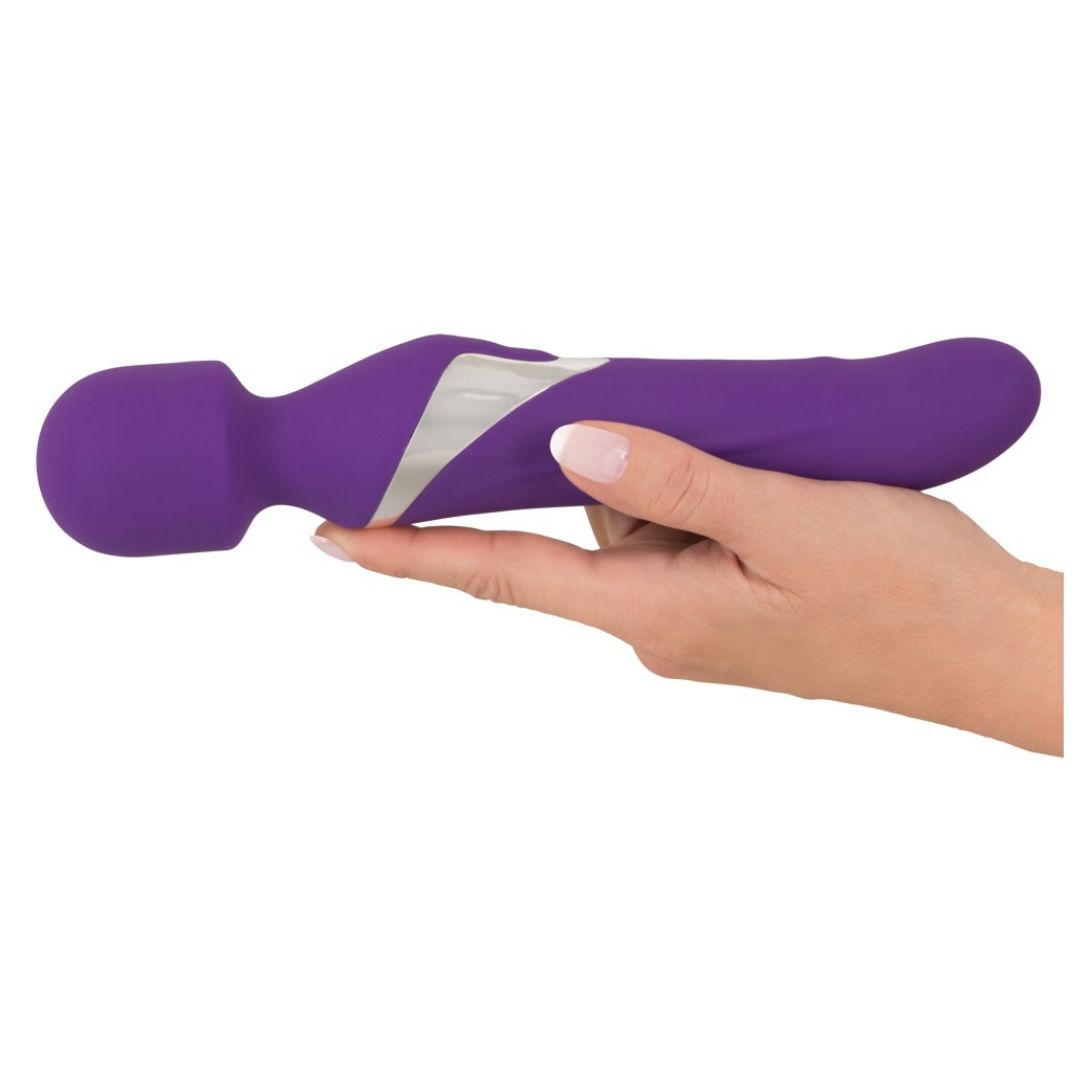 Lila Vibrator, in einer Hand gehalten. Silberfarbene Akzente. Abgerundete Form mit einem Kopf.