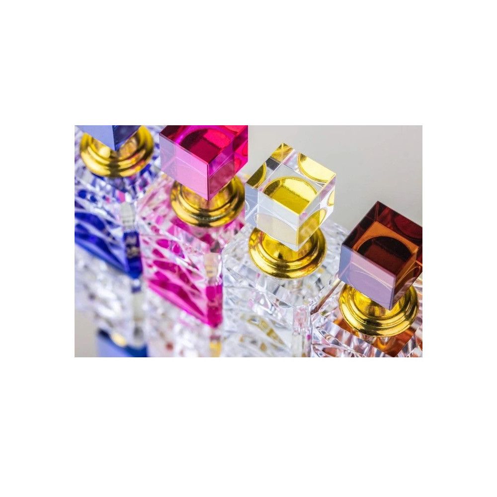 Mehrere Flakons mit quadratischen, farbigen Deckeln. Goldfarbene Verschlüsse. Kristallklares Glas mit Facettenschliff.