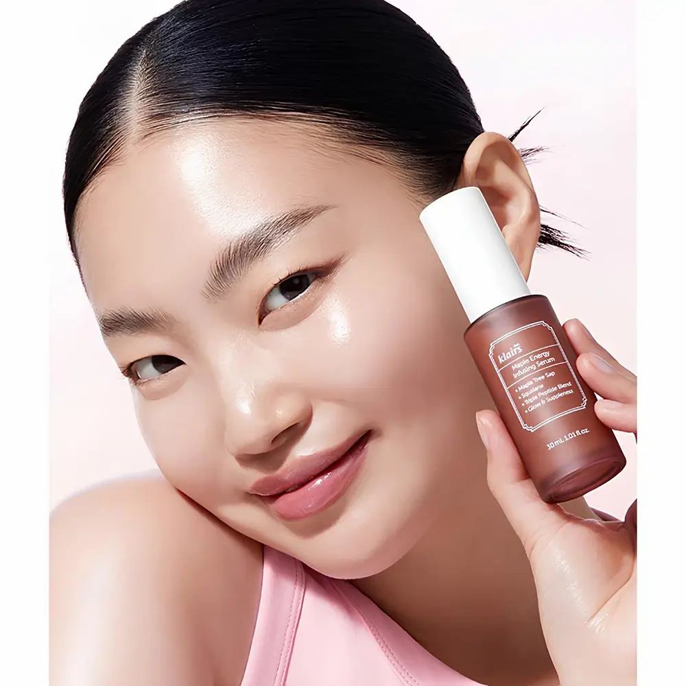 Frau hält eine braune Flasche. Aufschrift: klairs Maple Energy Infusing Serum. 30 ml.