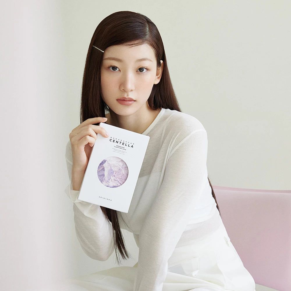 Frau hält eine weiße Box mit Gesichtsmaske. Text: MADAGASCAR CENTELLA, Poremizing Clarifying Mask.