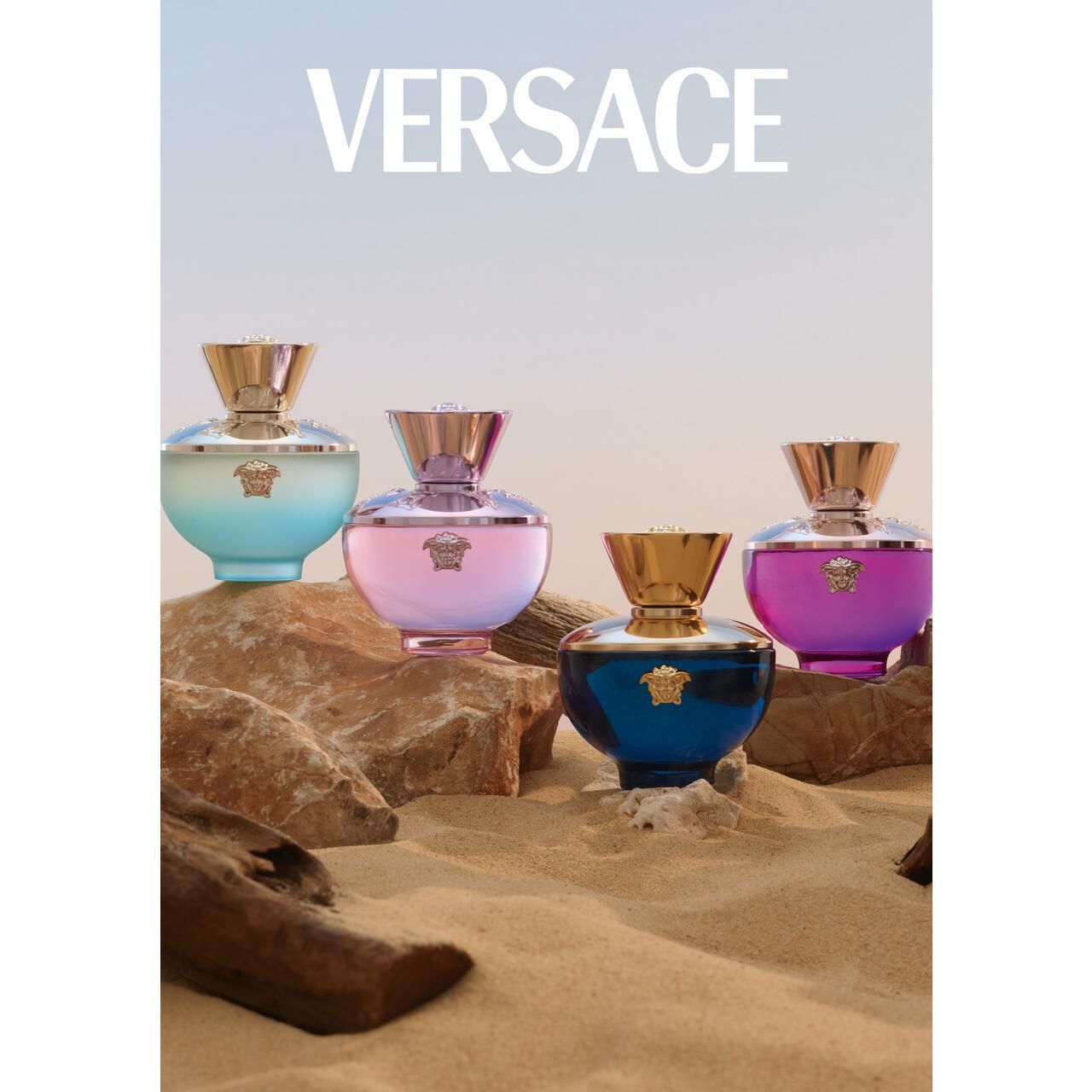 Vier Versace Dylan Blush Pink Eau de Parfum Flakons auf Sand und Holz. Flakons in verschiedenen Farben. Hintergrund: Meer und Himmel.