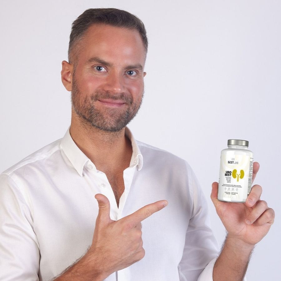 Mann hält eine weiße Flasche "BEST LAB URO BEST" in der Hand. Er zeigt mit dem Finger auf die Flasche.