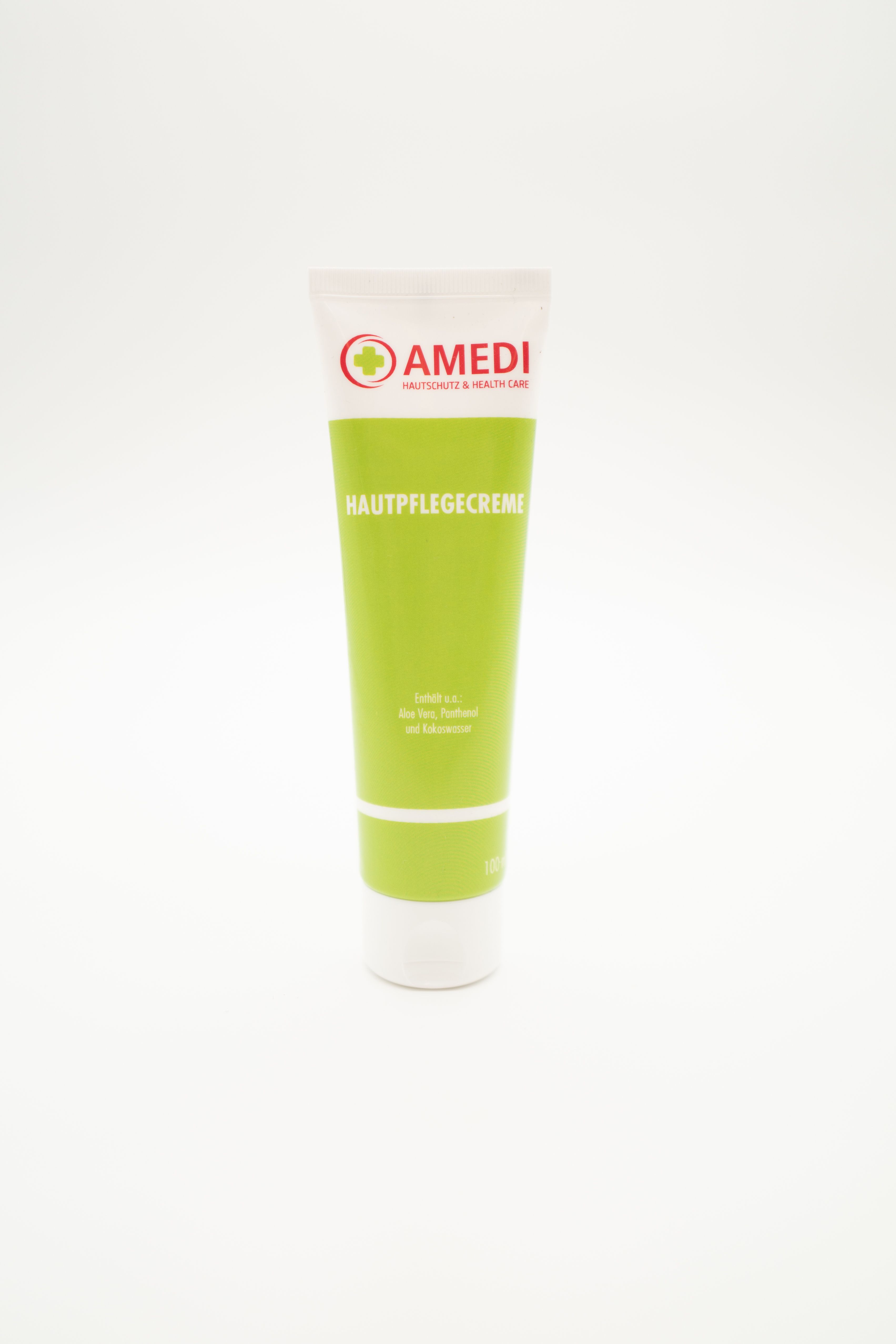Grüne Tube mit weißem Deckel. Aufschrift: AMEDI, Hautpflegecreme. Logo mit rotem Kreuz. Text in Deutsch.