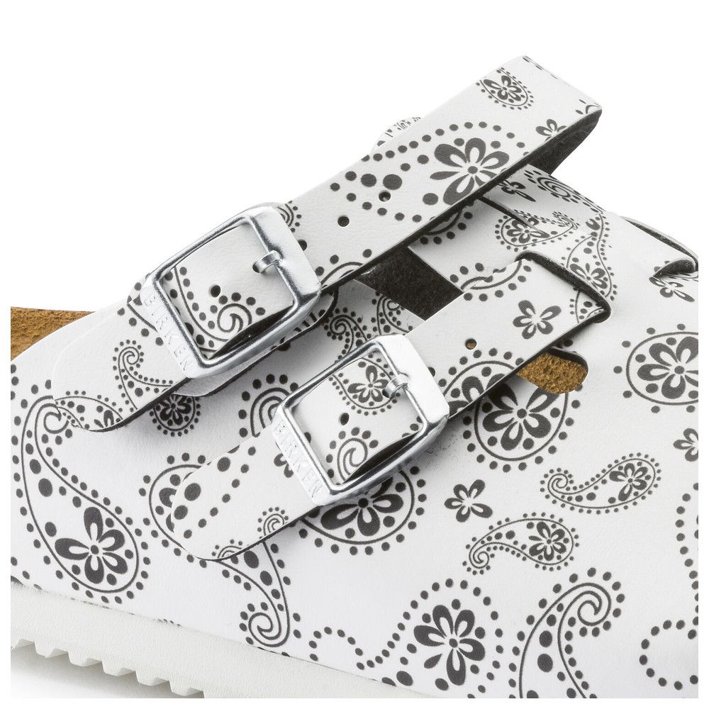 Detailansicht eines Clogs mit Paisley-Muster. Weiß mit schwarzem Muster. Zwei Schnallen. Korkfußbett.