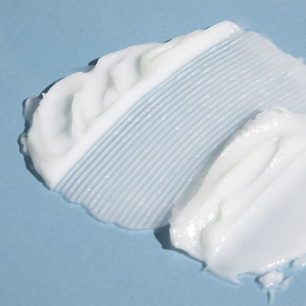 Nahaufnahme von weißer Creme auf blauem Hintergrund. Zwei Kleckse, Textur sichtbar.