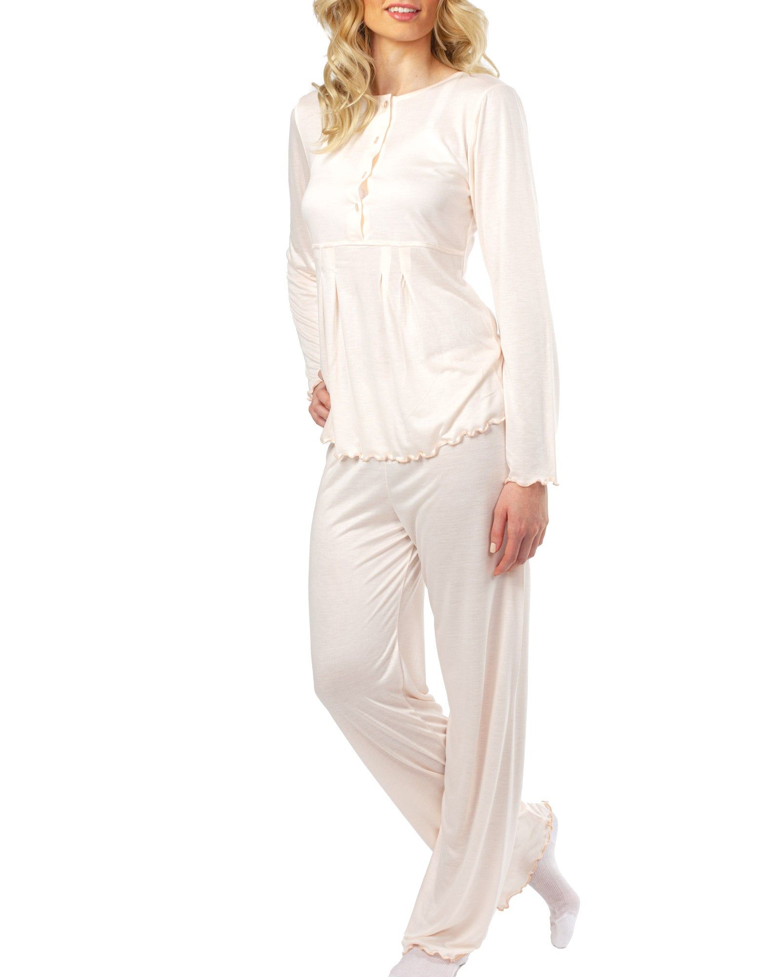 Rosa Pyjama-Set. Langarm-Oberteil mit Knöpfen, Rüschensaum. Lange Hose. Frau trägt das Set.