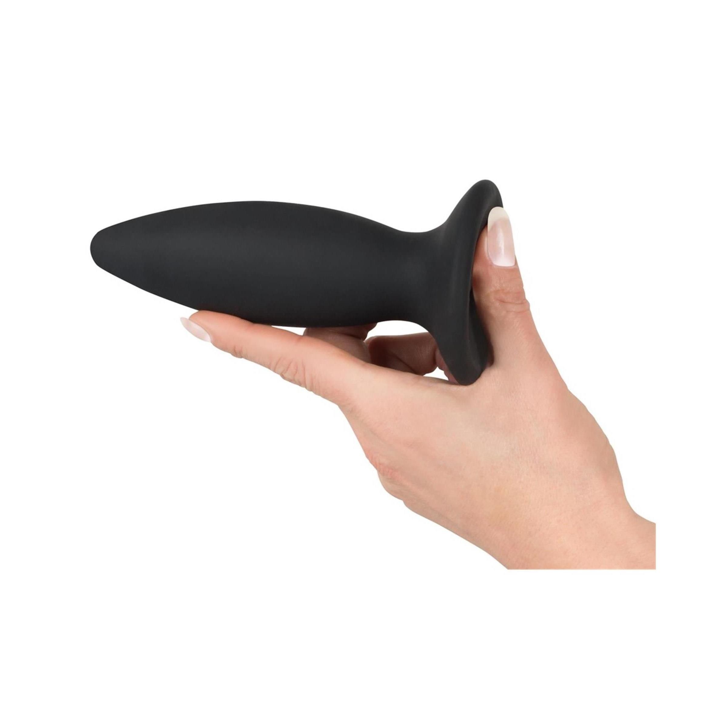 Schwarzer Plug in einer Hand gehalten. Kegelförmig mit breiter Basis.