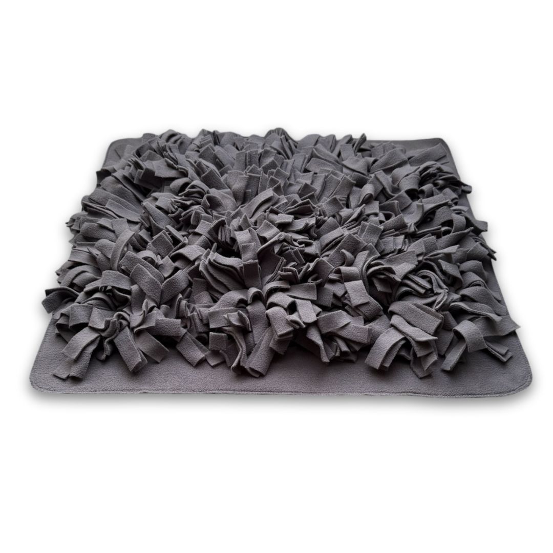 Ein grauer Schnüffelteppich mit vielen Stoffstreifen. Rechteckige Form.