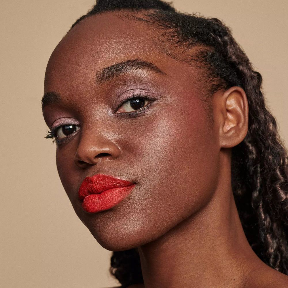 Porträt einer Frau mit roten Lippen. Dunkle Haut, Zöpfe.