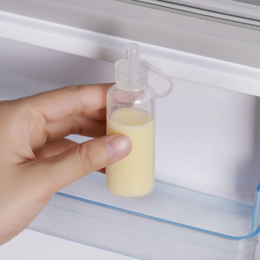 Transparenter Behälter mit Flüssigkeit, gehalten von einer Hand. Im Kühlschrank.