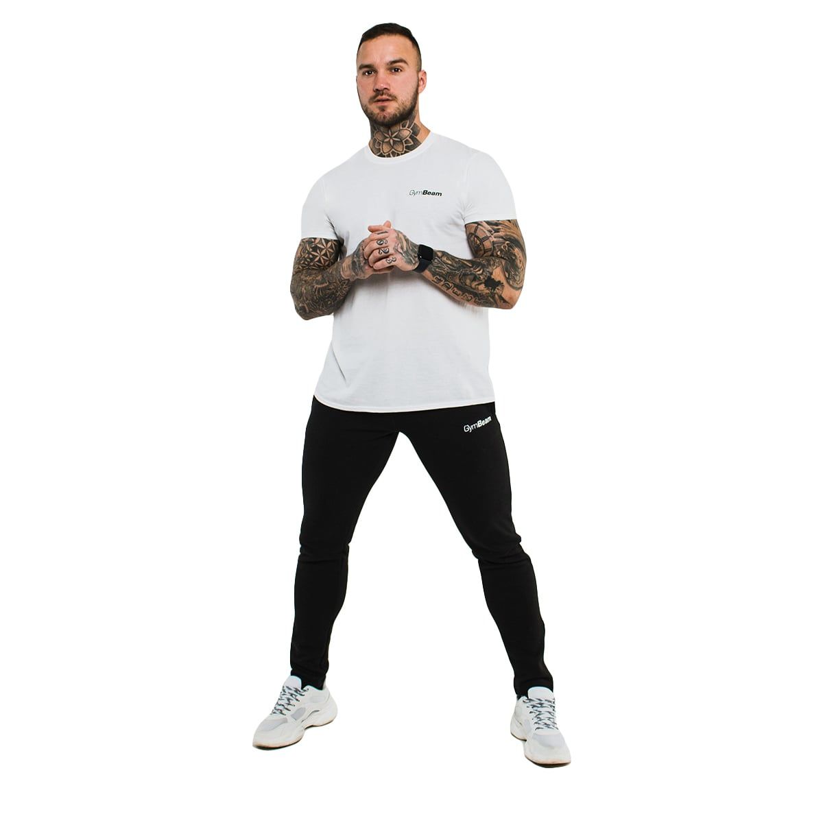 Mann in weißem GymBeam T-Shirt und schwarzen Hosen, steht frontal. Weiße Turnschuhe.