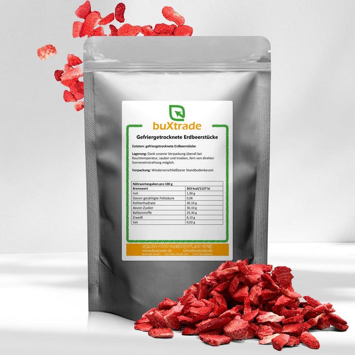 Beutel mit gefriergetrockneten Erdbeerstücken und verstreuten Erdbeerstücken. Etikett mit Produktinformationen und Marke buXtrade.