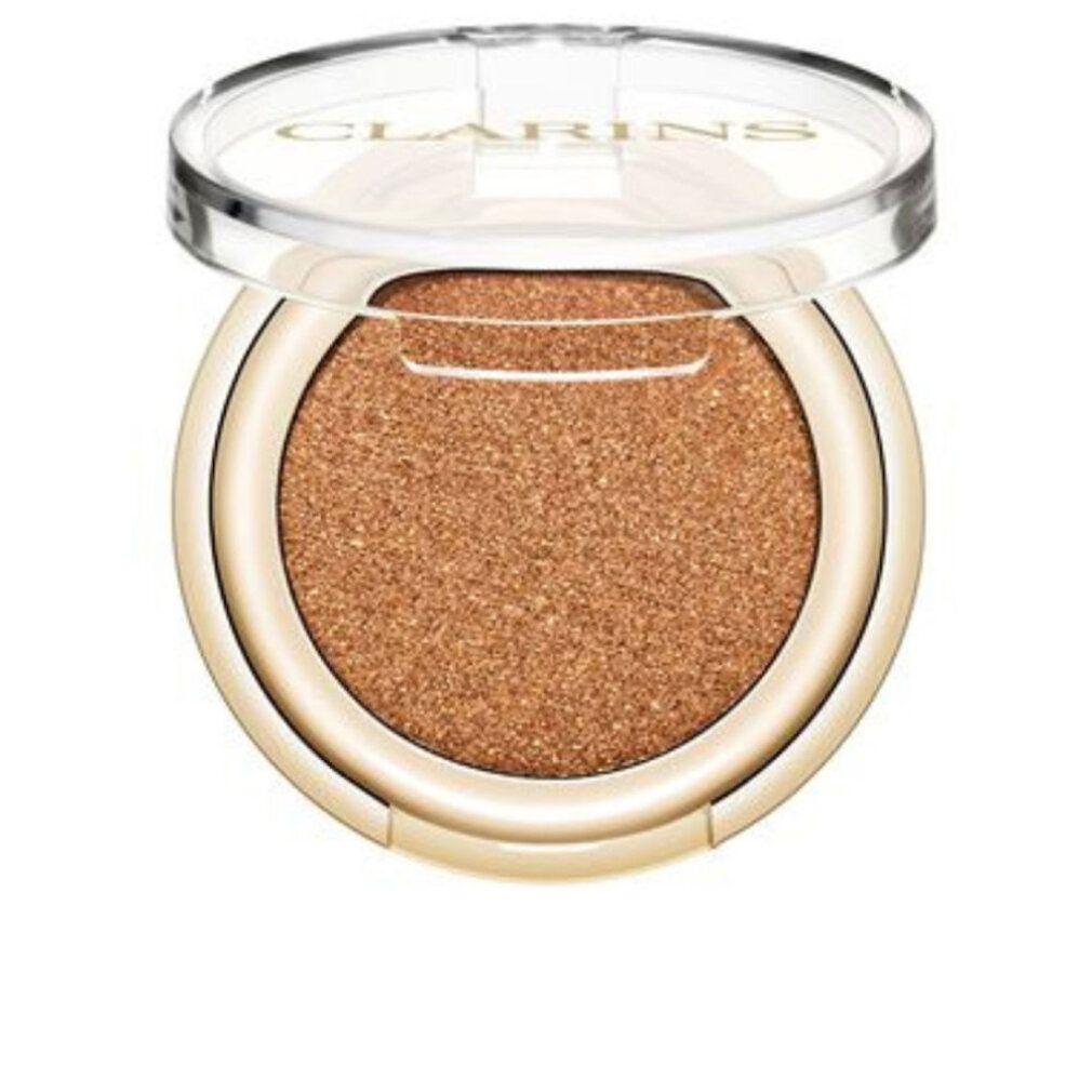 Clarins Lidschatten. Runde, goldfarbene Dose mit goldfarbenem Lidschatten. Transparenter Deckel mit Clarins-Logo.